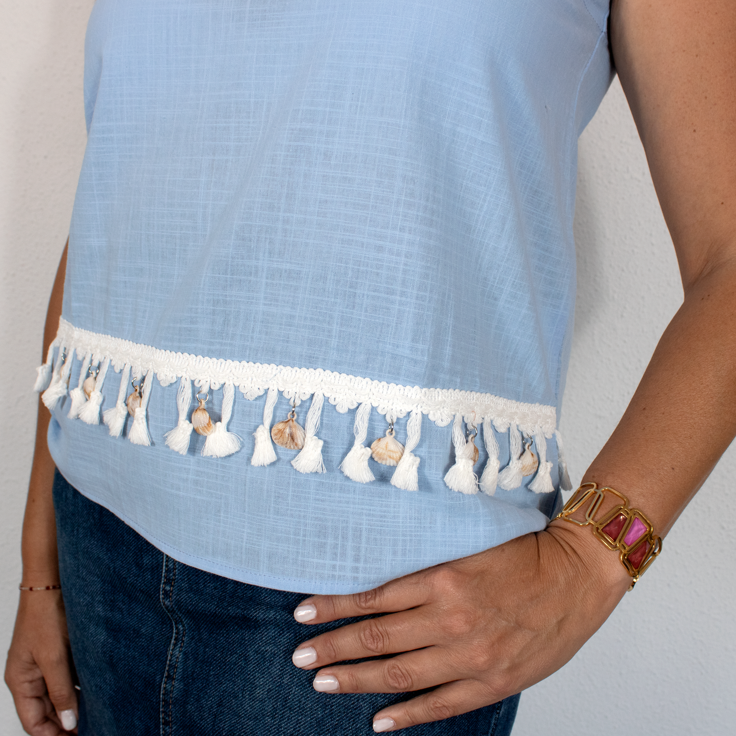 Blusa celeste con detalles decorativos, encaje y borlas